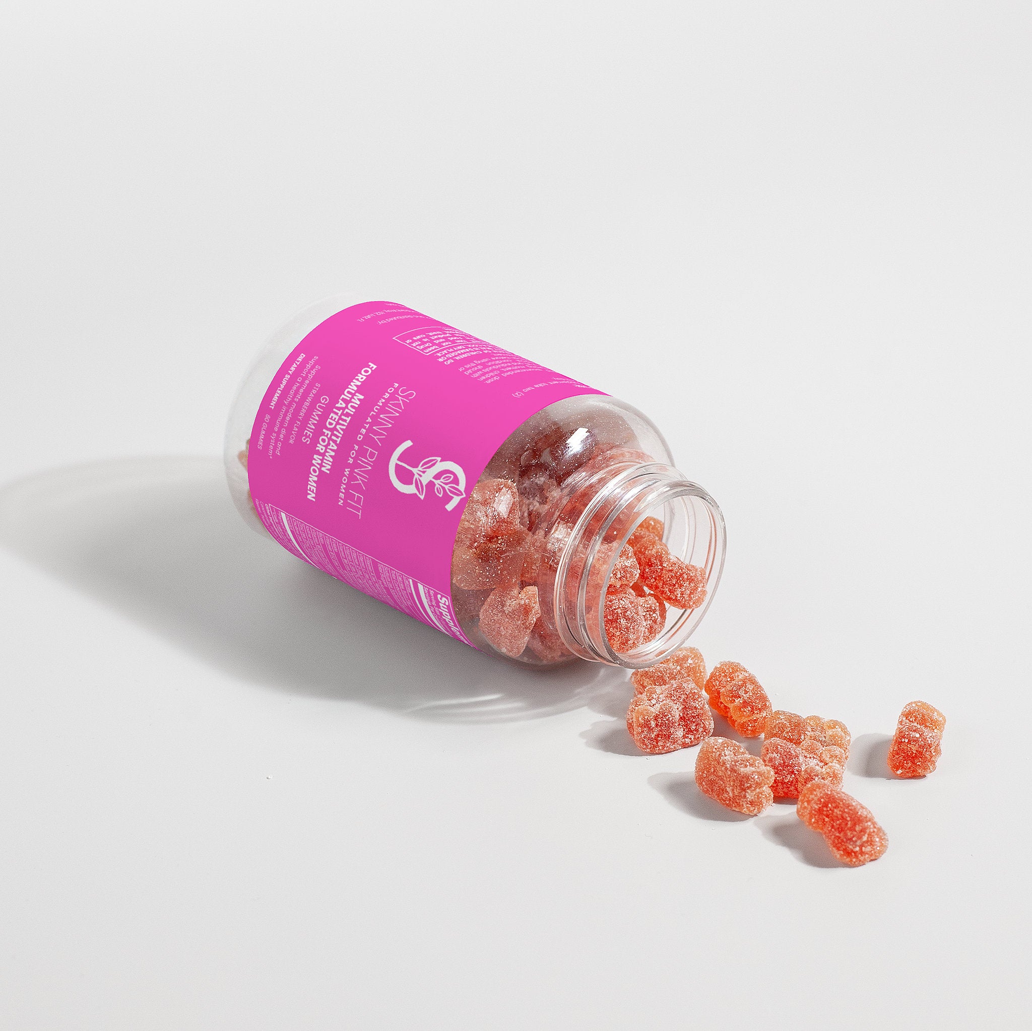 Pink jar of gummy supplements with scattered gummies on a light background, Skinny Pink Fit